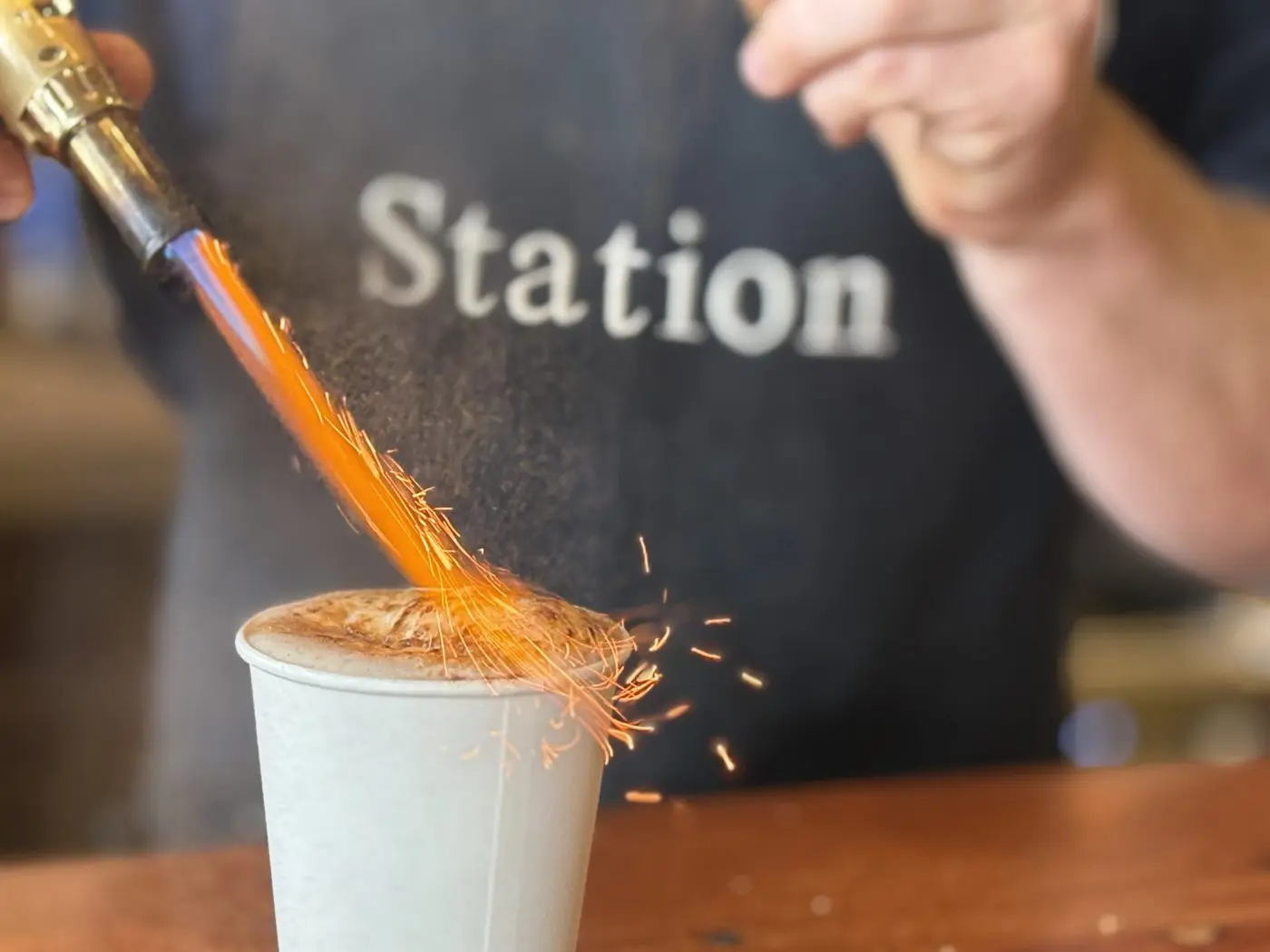 A barista torching the sugar on a creme brulee coffee at The Station at Esteem Surf Co. in Pismo Beach